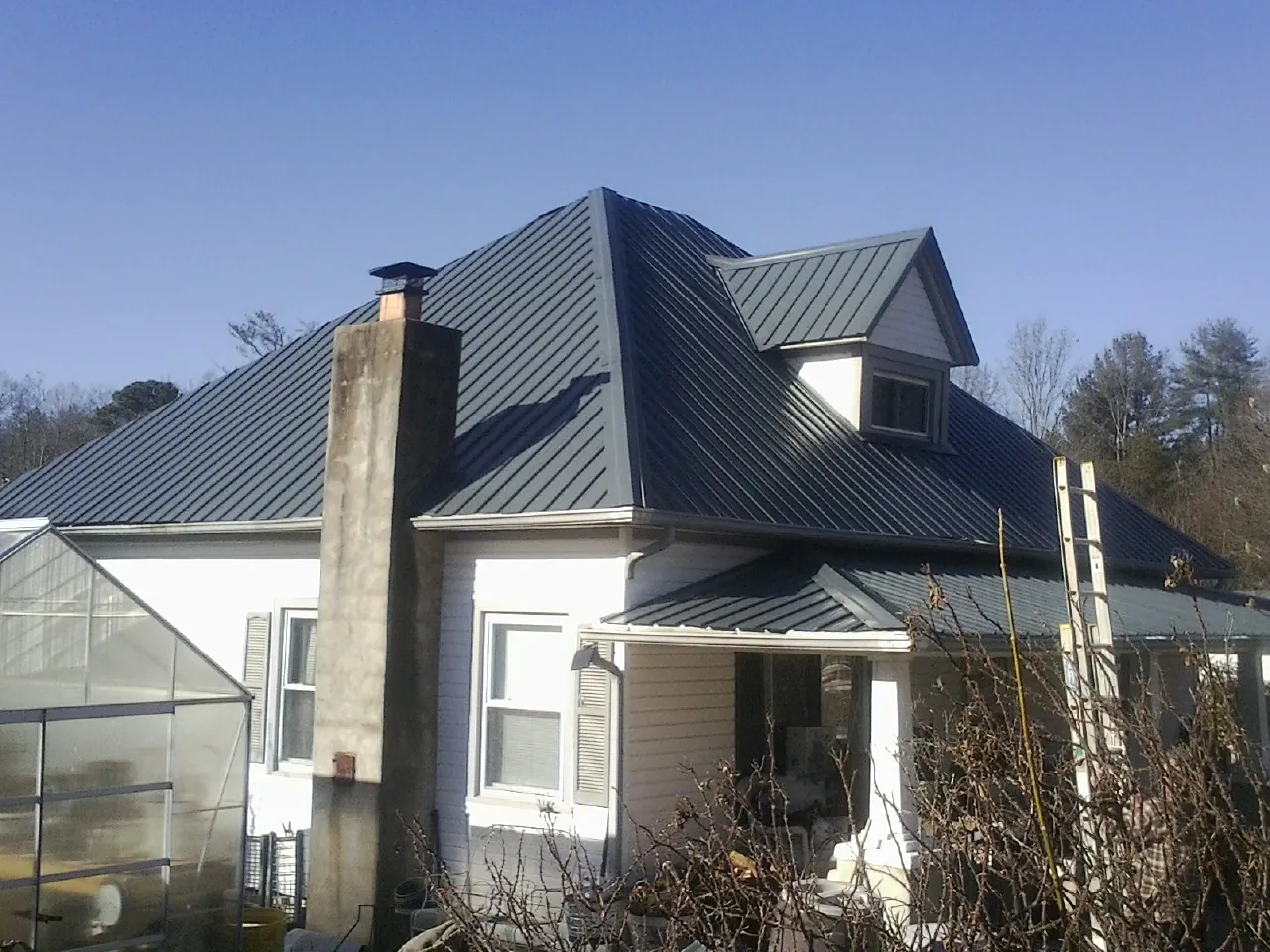 Dark blue standing seam metal roof on a white farmhouse with dormer — Slate & Tile Roof Repair by Roofing Brothers in Worden