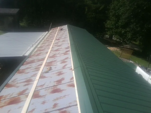 Old rusted panels beside newly installed green metal roofing — Wind Damage Roof Repair by Roofing Brothers in Worden