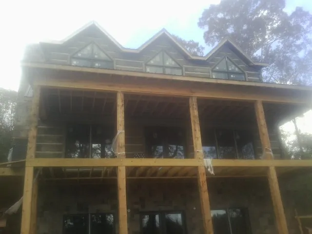 Dormers and porch framing on a large log home under construction — Roof Coating work by our crew in Worden
