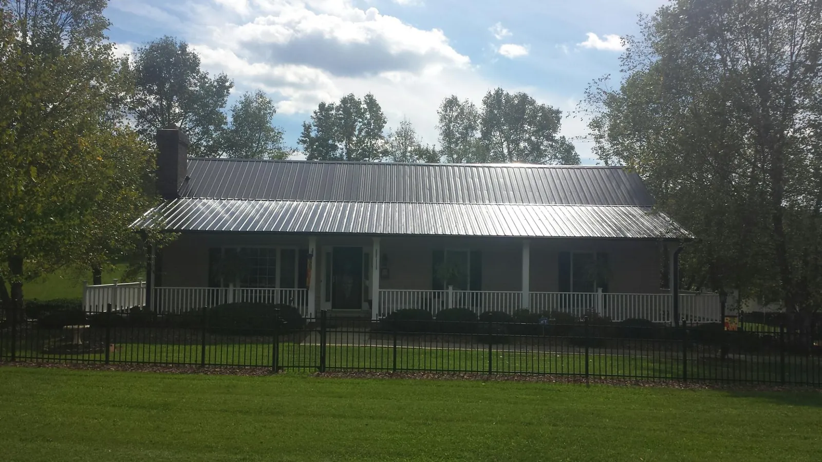 Gray metal roof on a brick ranch with a full width front porch — Gutter Guard Installation work by our crew in Worden