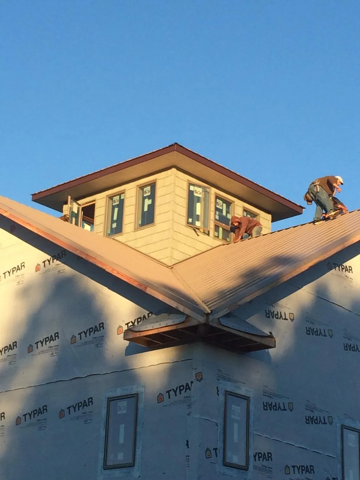 Roofers working around a rooftop cupola on a new metal roof at sunset — Roof Waterproofing in Worden by Roofing Brothers